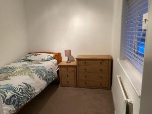 a bedroom with a bed and a dresser and a window at Sunnyhill in Witley