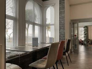 een eetkamer met een tafel, stoelen en ramen bij Esplanade Hotel - Clacton On Sea, Beachfront Hotel by OYO in Clacton-on-Sea