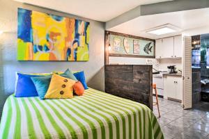 a bedroom with a bed with colorful pillows and a kitchen at Bright Gulf Coast Escape - 8 Mi to Johns Pass! in St Pete Beach