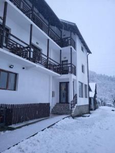 a white building with snow on the ground at livada-cu-meri in Căpăţîneni-Ungureni