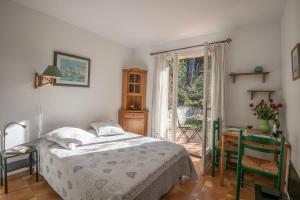 1 dormitorio con cama, mesa y ventana en Le Mas des Gardettes, en Saint-Paul-de-Vence