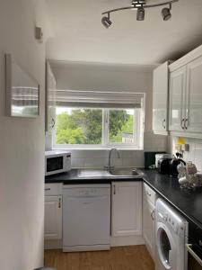 a white kitchen with a sink and a dishwasher at Sunnyhill in Witley