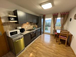 a kitchen with gray cabinets and a table with a microwave at Ferienhaus Frei 3 Budget in Titisee-Neustadt