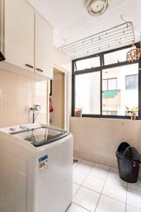 a white kitchen with a sink and a window at Apartamento Encantador II - Enseada Guarujá - 100 metros da Praia in Guarujá