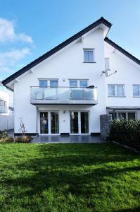a white house with a lawn in front of it at Modern Wohnen I Smart TV I Terrasse I 2x Parkplatz I 2 Schlafzimmer I 6 Schlafplätze in Bad Oeynhausen
