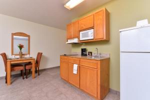 a kitchen with a white refrigerator and a table at Americas Best Value Inn & Suites-Winnie in Winnie