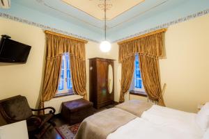 a bedroom with a bed and a chair and two windows at Archontiko Naoumidi in Portariá