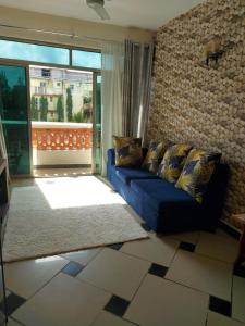 a living room with a blue couch and a large window at Mombasa Shanzu One Bedroom Apartment /Swimming Pool/Free WiFi in Mombasa