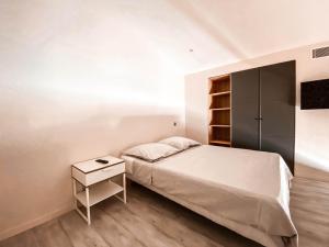 biała sypialnia z łóżkiem i stolikiem nocnym w obiekcie Residence du Batailler w mieście Le Lavandou