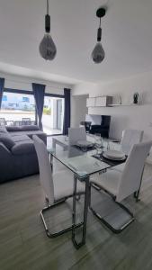 sala de estar con mesa de cristal y sillas blancas en Casilla de Costa Luxury home en La Oliva