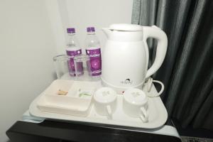 a tray with a coffee maker and bottles and cups at Felix Inn - Manyata Tech Park in Bangalore