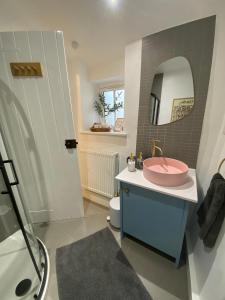 a bathroom with a pink sink and a mirror at Jacks Cottage, Curbar in Curbar