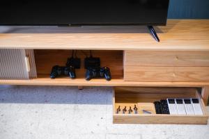 a wooden entertainment center with a tv and video game controllers at monstera homestay near Tambun, Ipoh Garden East in Ipoh