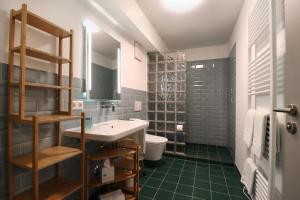 a bathroom with a sink and a toilet and green tiles at S12 - Boardinghouse by Hotel Trezor in Singen