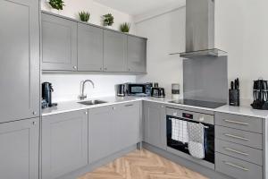 uma cozinha com armários brancos e electrodomésticos de aço inoxidável em Finest Retreats - Market View em Ripon