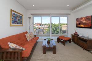 a living room with an orange couch and a large window at N3A1 - New, Nice, for Long and Short Stay in Asunción