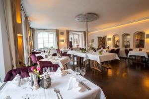 a dining room with white tables and purple chairs at Hotel Weisses Ross in Memmingen
