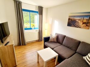 een woonkamer met een bank en een tv bij Inselstrand in Horumersiel