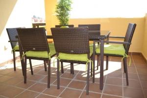 einen Tisch und Stühle mit grünen Kissen auf der Terrasse in der Unterkunft Duquesa Village 2115 in Manilva