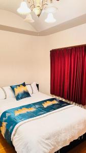 um quarto com uma cama grande e uma cortina vermelha em 田町ハウス em Takamatsu