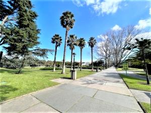 un parc avec des palmiers et un trottoir dans l'établissement playa Santa Cristina, à Oleiros