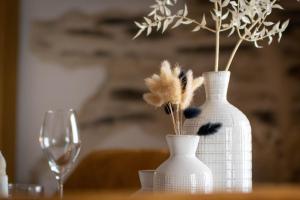 zwei weiße Vasen mit Federn auf einem Tisch mit Glas in der Unterkunft Love Room Bohème Les Petits Plaisirs in Angers