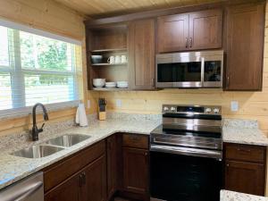 a kitchen with a stove and a sink and a microwave at The Brick House: Brand NEW! 3 Bedroom Home with private driveway in Pigeon Forge