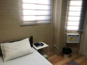 a bedroom with a bed and a window and a table at Maine City Residences Leveriza in Manila