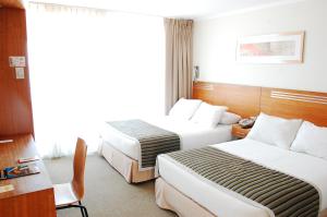 ein Hotelzimmer mit 2 Betten und einem Schreibtisch in der Unterkunft Alto del Sol Costanera Antofagasta in Antofagasta