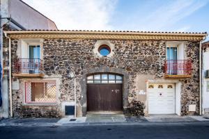 un edificio de piedra con puerta y garaje en Appartement d'une chambre avec piscine partagee jardin clos et wifi a Marseillan a 6 km de la plage, en Marseillan