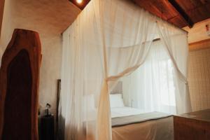 uma cama com cortinas brancas e uma janela em Baguá Bangalôs em Alto Paraíso de Goiás
