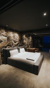 uma cama grande num quarto com uma parede de pedra em Baguá Bangalôs em Alto Paraíso de Goiás