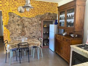 una cucina con tavolo, sedie e parete in pietra di Casa Vacanza Sa dommu de Teresa a Nebida