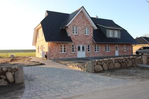 a red brick house with a black roof at DHH Buhne in Karolinenkoog