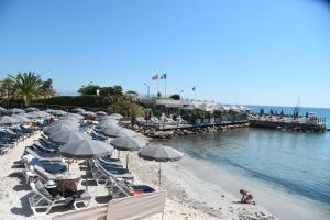 a beach with chairs and umbrellas and a pier at Royal Antibes - Luxury Hotel, Résidence, Beach & Spa in Antibes