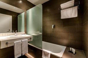 a bathroom with a sink, mirror, towel rack and towel dispenser at YIT Vía Sevilla Mairena in Mairena del Aljarafe