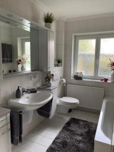 biała łazienka z umywalką i toaletą w obiekcie Ferienhaus Bendestorf, Waldweg 38,Nähe Hamburg w mieście Bendestorf