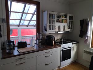 cocina con armarios blancos, fogones y ventana en Nedre Kjellerstuvei, Oslo House Second floor, en Lillestrøm