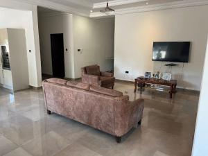 sala de estar con 2 sofás y TV en Laffie House, en Sukuta