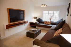a living room with a couch and a flat screen tv at Duck Cottage in the centre of Henley in Henley on Thames
