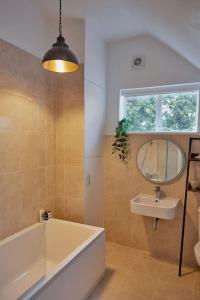 a bathroom with a tub and a sink and a mirror at Duck Cottage in the centre of Henley in Henley on Thames