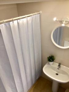 uma casa de banho com uma cortina de chuveiro branca e um lavatório. em Trill Mirasol B estudio 1a linea mar em L'Estartit