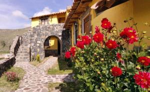 Lodge Mirador San Antonio- Colca في Coporaque: مبنى أمامه زهور حمراء