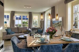 uma sala de estar com uma mesa de madeira e cadeiras azuis em Haus Sylter Momente em Westerland