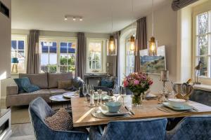 a living room with a wooden table and blue chairs at Haus Sylter Momente in Westerland (Sylt)