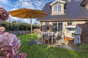 a patio with an umbrella and a table and chairs at Haus Sylter Momente in Westerland