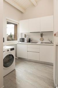 a kitchen with white cabinets and a washing machine at Vicolo Zini Apartments in Verona
