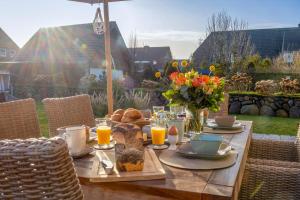 a wooden table with breakfast food and orange juice at Haus Westerländer Perle in Westerland