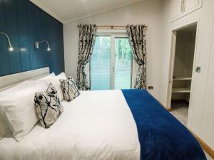 a bedroom with a white bed with blue walls and a window at Bluebell Lodge in Skipton