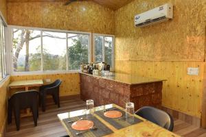 un restaurante con barra, mesas y sillas en santanas wooden cottages en Bogmalo